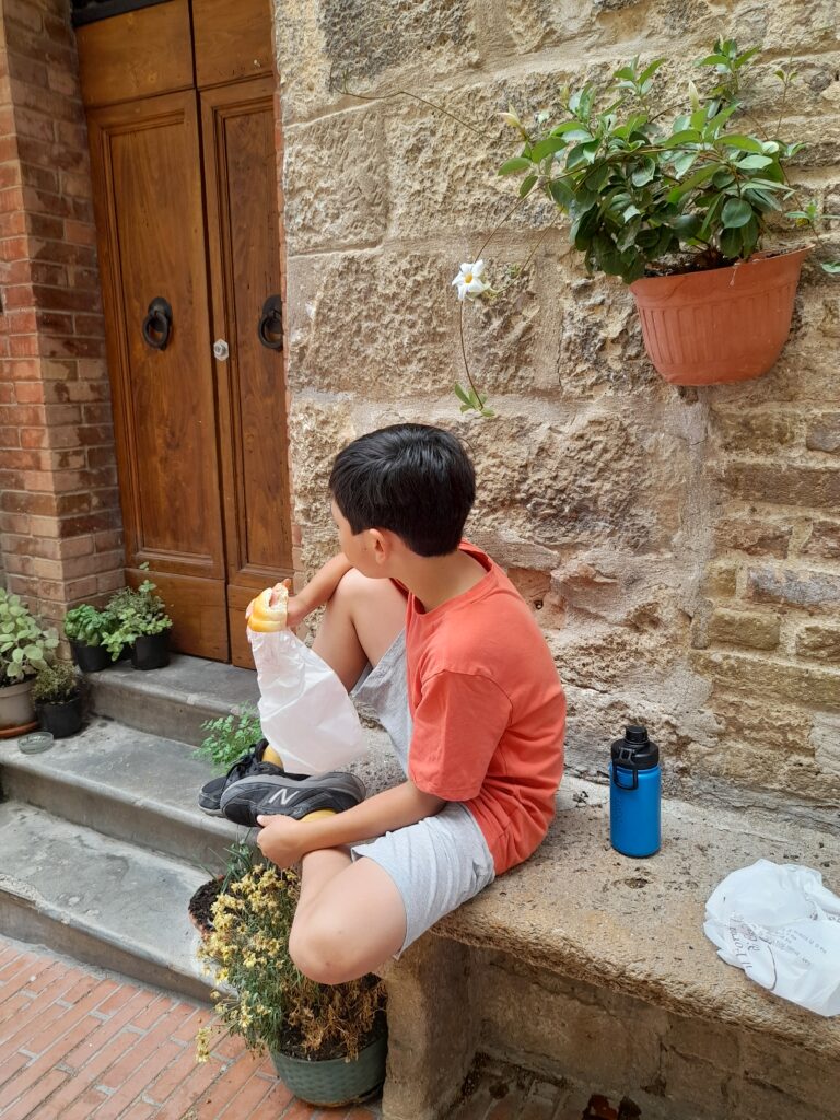 이탈리아 오래된 마을에서 10대 어린 남자아이가 파니노를 먹고있는 옆모습