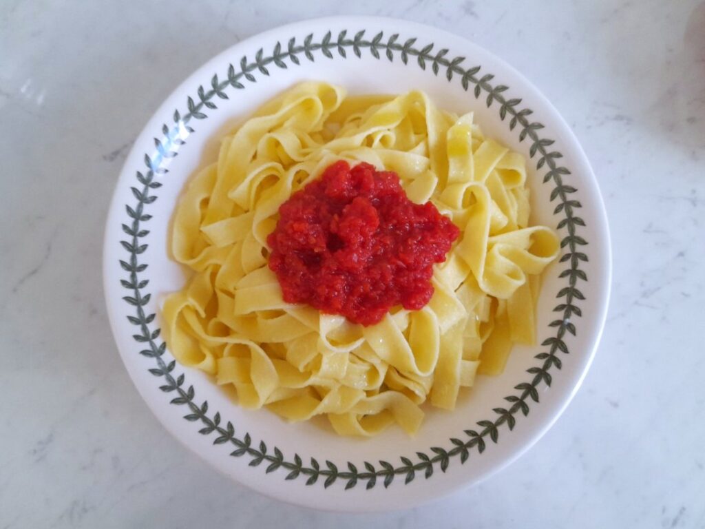 시에 담긴 탈리아텔레 파스타 위에 토마토 소스를 올린 모습