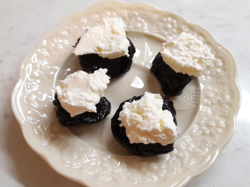 접시에 올린 말린 자두 위 마스카르포네 치즈 한입 간식