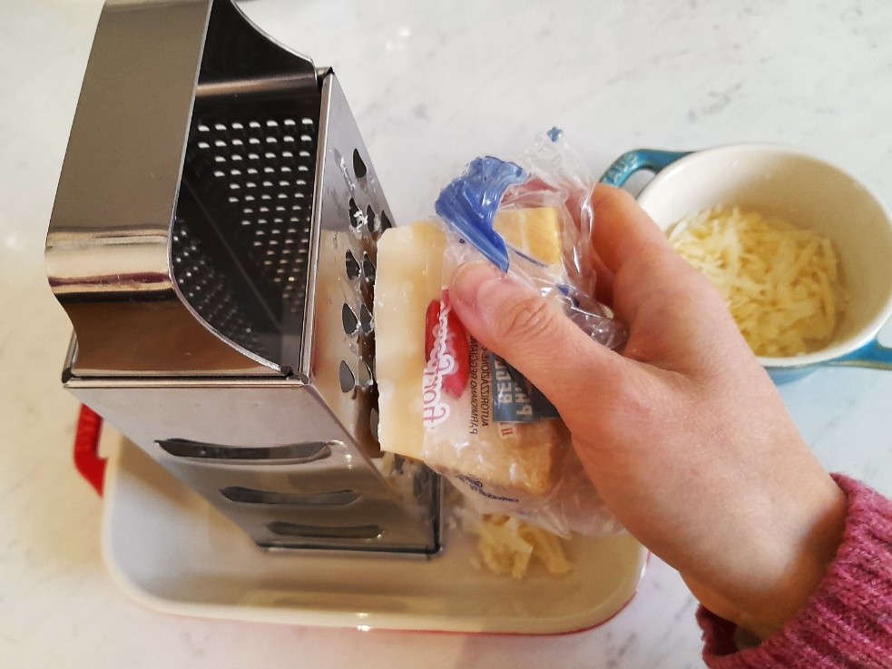 강판에 파르미지아노 치즈를 손으로 갈아 준비하는 모습