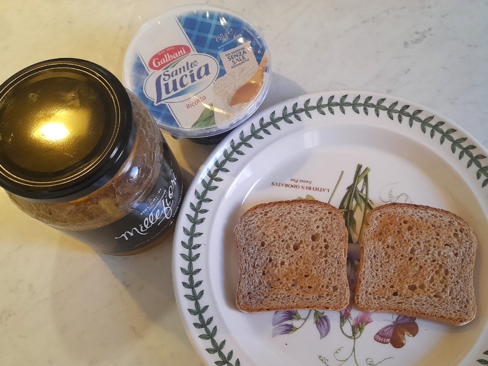 접시 위 토스트 두 장과 리코타, 꿀이 함께 놓인 아침 준비 재료