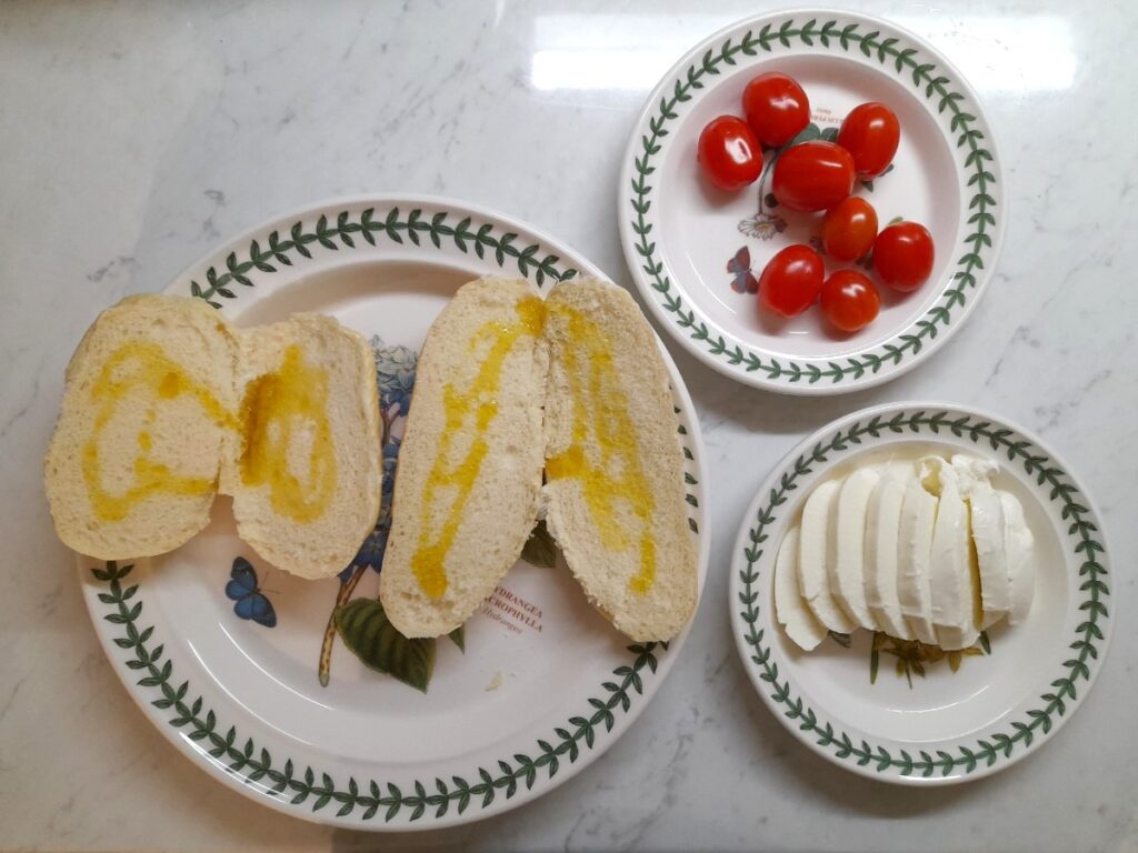 파니노 재료인 방울토마토, 모차렐라 치즈, 올리브유를 뿌린 파니노알라떼가 각각 접시에 담겨있다