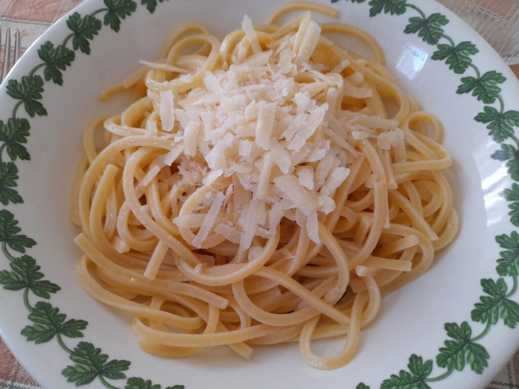 접시에 담긴 파스타 위에 파르미지아노 치즈와 버터를 올린 한 끼