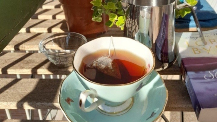 햇살 드는 발코니 테이블 위 차 한 잔과 초록 식물