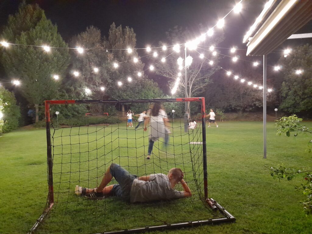 이탈리아 야외 정원에서 열린 아이 생일파티 풍경, 전구 조명 아래에서 아이들과 부모들이 함께 있는 모습